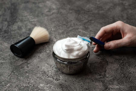 Hand holds disposable razor on gray wall backgroundの写真素材