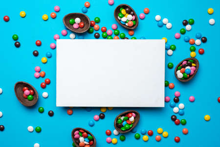 Empty mockup white blank on a blue  Easter background. Multi-colored candy. - Copyspaceの写真素材
