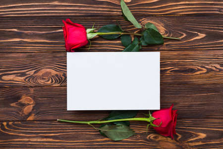 Red roses and blank piece of paper on wooden board, valentines day background, wedding dayの写真素材
