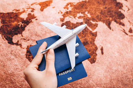 Hand holding NEUTURAL passport on the world map background with model airplane / travel concept / selective focusの写真素材