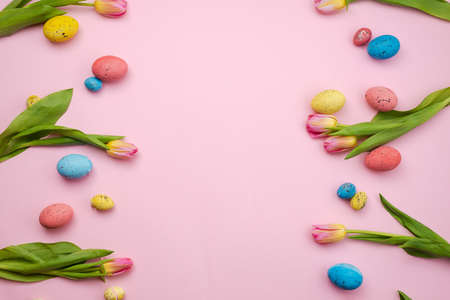 Beautiful pink tulips and colored Easter eggs on a pink background.の写真素材