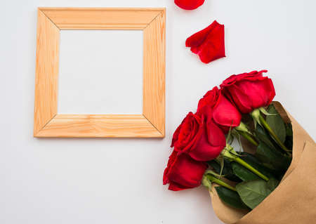 On a white background there are beautiful red roses and a frame. Place for text, copy spaceの写真素材
