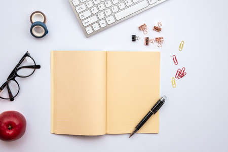White desk with astationery, open empty diary and other objects on itの写真素材