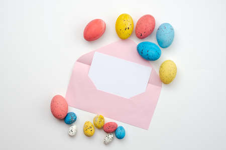 Beautifully colored Easter eggs and a beautiful blank envelope on a white backgroundの写真素材