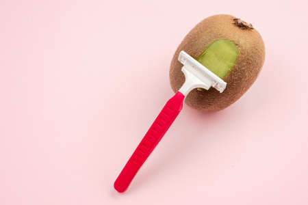 Kiwi fruit and razor on pink background. Hair removal concept. Creative minimal concept with copy space.の写真素材