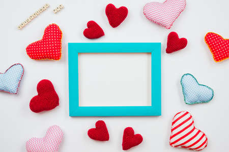 Multicolored hearts and a frame of blue are spread on a white background. Theme for Valentine's Day. place for textの写真素材
