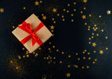 Holiday gift tied with red ribbon on black Christmas backgroundの写真素材