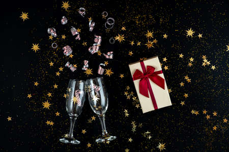In anticipation of the holiday. Glasses, gold sequins and candies on a black background.の写真素材