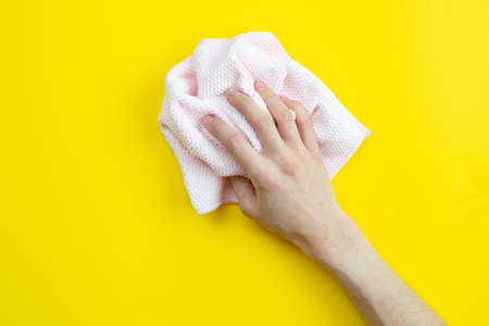 On a yellow background a hand holds a rag. Cleaning concept.の写真素材