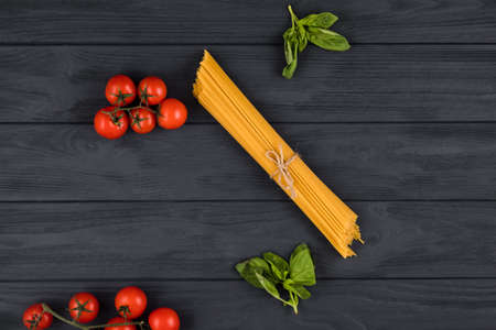 On a dark background are Italian ingredients: pasta, tomatoes, basilの写真素材