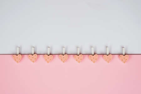 Background for Valentine's Day holiday. Pink hearts and clothespins on a delicate pink and white background. Valentines day concept. Top view, flat layの写真素材