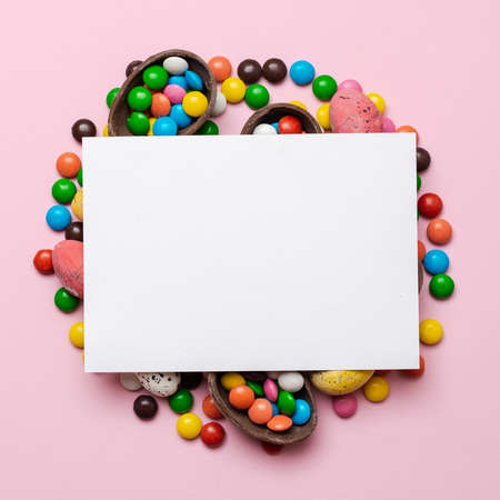 Empty template mockup white blank on a pink  Easter background. Multi-colored candy. - Copyspaceの写真素材