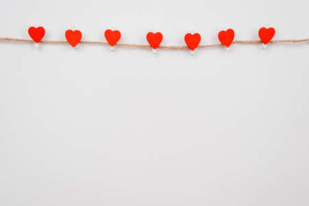 Red paper heart hanging on the clothesline on white wall. Place for advertisingの写真素材