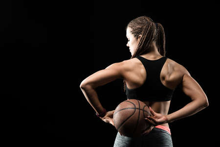 Young fitness girl with basketball ball on blackの写真素材