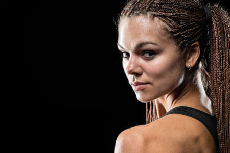 Portrait of a beautiful young sportswoman with dreadlocks on a black backgroundの写真素材