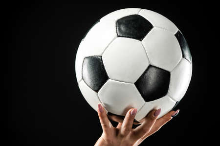 Classic soccer ball on female hand. Isolated over black backgroundの写真素材