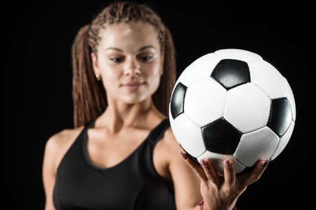 Young female soccer player standing and holding the ballの写真素材