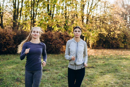 Two cute, fitness girls jogging in the park.の写真素材