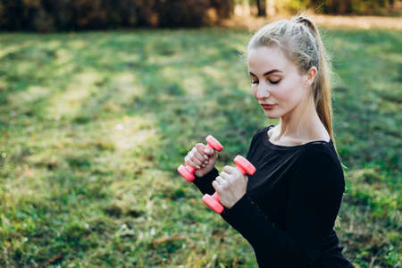 Girl with dumbbells training outdoorsの写真素材