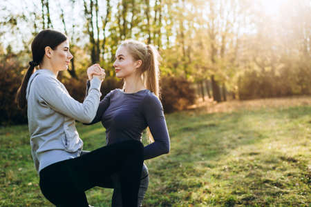 Two girlfriends perform face-to-face exercises in nature.の写真素材
