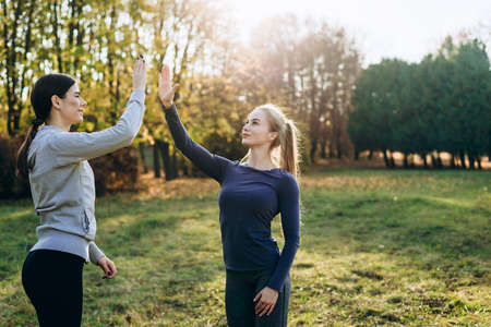 Two girls in the park are exercising and clapping their hands.の写真素材