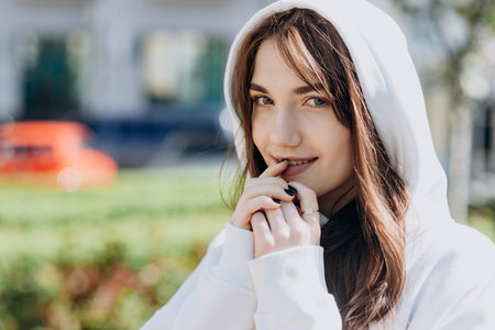 Beautiful brunette dressed in a hood, posing beautifully outdoorsの写真素材