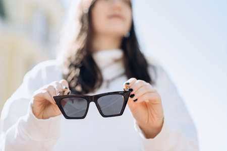 Brunette on a blurred background, in her hands clearly visible sunglasses, close-upの写真素材
