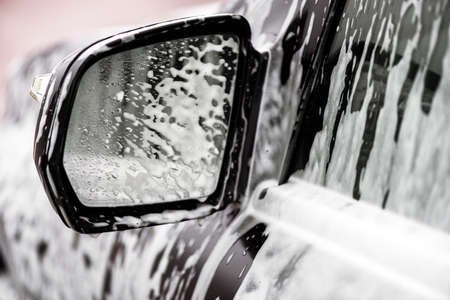 Closeup mirror of black car in the soap. Concept washing carの写真素材