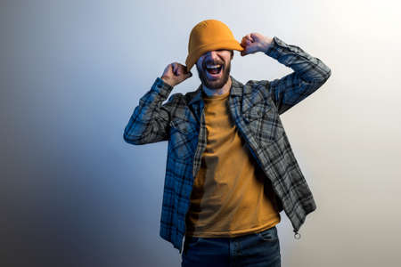 Fun bearded man wearing yellow hat with empty space for your logo and screamingの写真素材