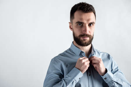 Studio shot portrait of romantic guy fastens a button on a shirt.の写真素材