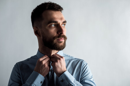 Studio face  male portrait with arms fastens a button on a shirt.の写真素材