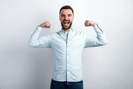 Portrait of funny man holds  his hands with clenching fists showing gesture power musclesの写真素材
