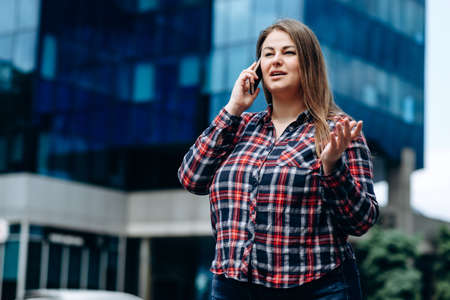 Pretty, business woman in a checkered shirt communicates on the phone on the background of the...