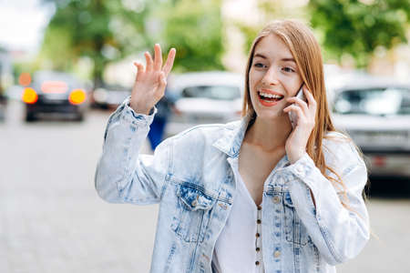 Beautiful, smiling girl talking on the phone talking on the phone, showing someone a congratulatory gestureの写真素材