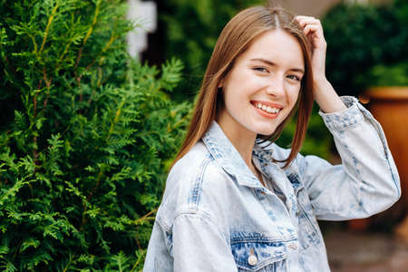 Portrait of young lovely woman in spring red flowers. The girl is standing near the green tree.の写真素材