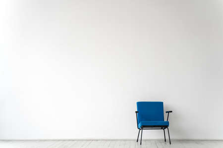 Empty room with a blue chair on a white wall backgroundの写真素材