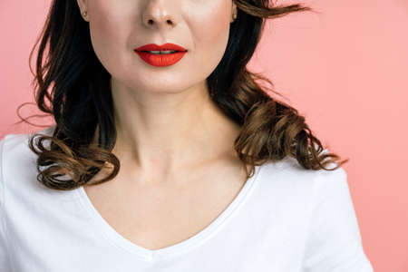 On a pink background, half of a woman's face, red lips. Portrait of a woman for advertising, copy space, place for text, blank wall.の写真素材