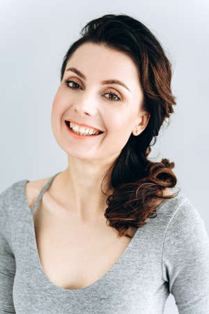 Portrait of a beautiful, young woman smiling looking at the camera. Girl posing isolated on gray wall.の写真素材