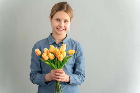 Little girl holding a bouquet of yellow tulips on a white background. Teen girl on a white background.の写真素材