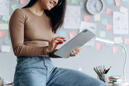 Close-up view, the girl leaned on the desktop, holding a tablet. The concept of modern technology and work in a modern office.の写真素材