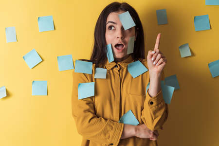 Charming girl with stickers on her face isolated on orange background. Cute girl showing finger on copy space, place for text.の写真素材