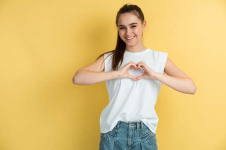 Portrait of a girl who smiles and makes a heart out of her fingers. Female hands in the shape of a heart.の写真素材