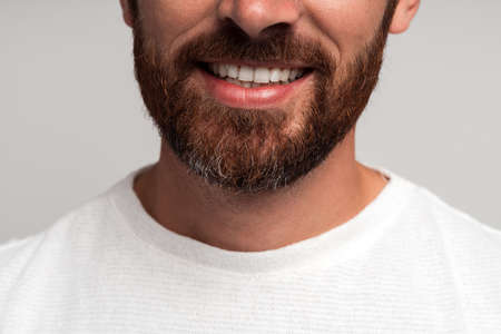 Close up portrait of happy handsome bearded businessman standing and smiling. Indoor studio shot,...