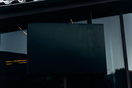 Close up of empty black poster on concrete building. Trees and sunlight in the background. Mock upの写真素材