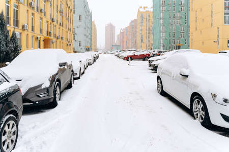 City street covered by snow after blizzard. Rows of parked cars in the street on a snowstorm winter day. Cyclones conceptの写真素材