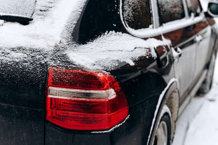 Snowfall, car covered with snow, cropped view. Snowy winter, lots of snow. Close up view of the car in the snow-covered parking. Cold snowy winter weather conceptの写真素材