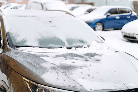 Cropped view of the car hood under the snow after a snowfall. Cars in the snow-covered parking lot. Snowy winter and lots of snow conceptの写真素材