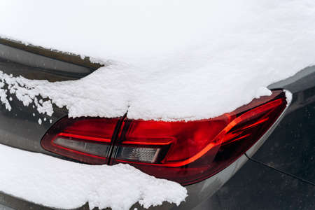 Cropped view of the car suffered after snow cyclone. Close up of a car standing on a snowy road....
