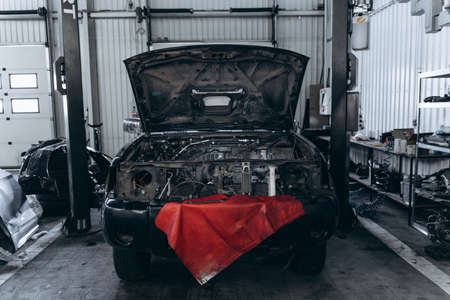 Seasonal checkup of the car. Black car with opened trunk standing at the garage at the service....