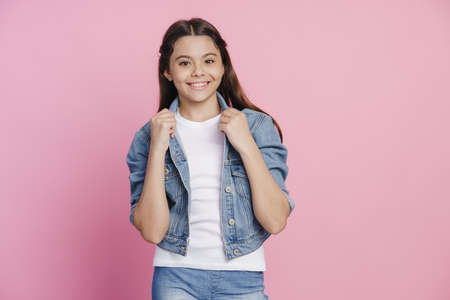 Modern teenage girl dressed in casual style, denim jacket and jeans on a pink background. Cute...